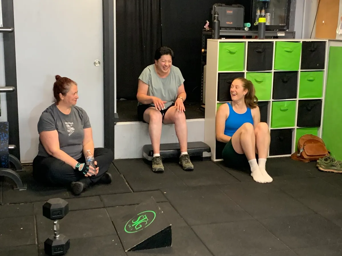 Three women sitting and laughing together between sets.